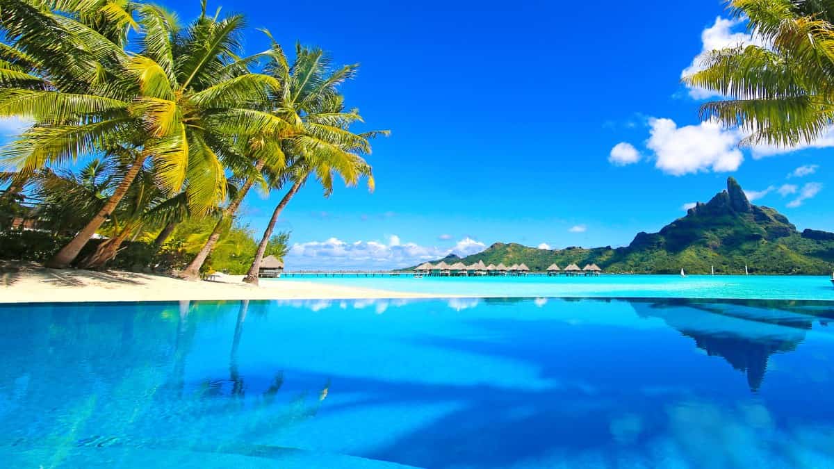 a view of the azure waters, beach, mountains, and overwater bungalows in Bora Bora