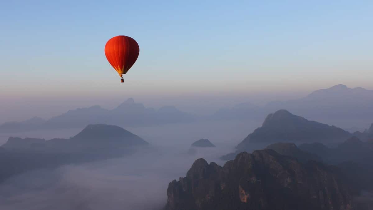 Hot air balloon floating above a stunning landscape at sunrise